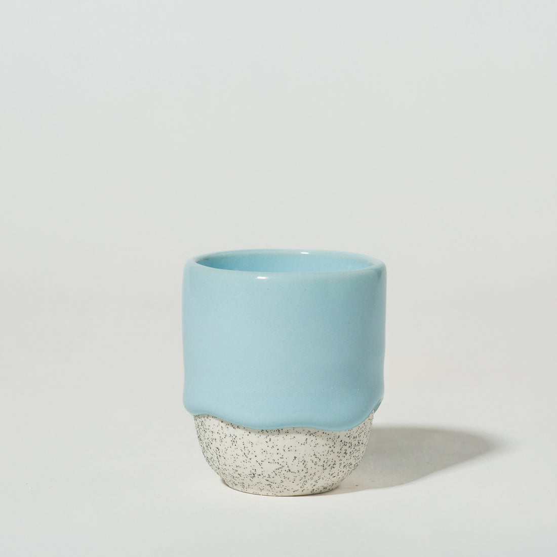 A blue ceramic espresso cup with a speckled white bottom.