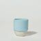 A blue ceramic espresso cup with a speckled white bottom.