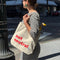 Woman holding a tote bag with 'not neutral' text on a city street.