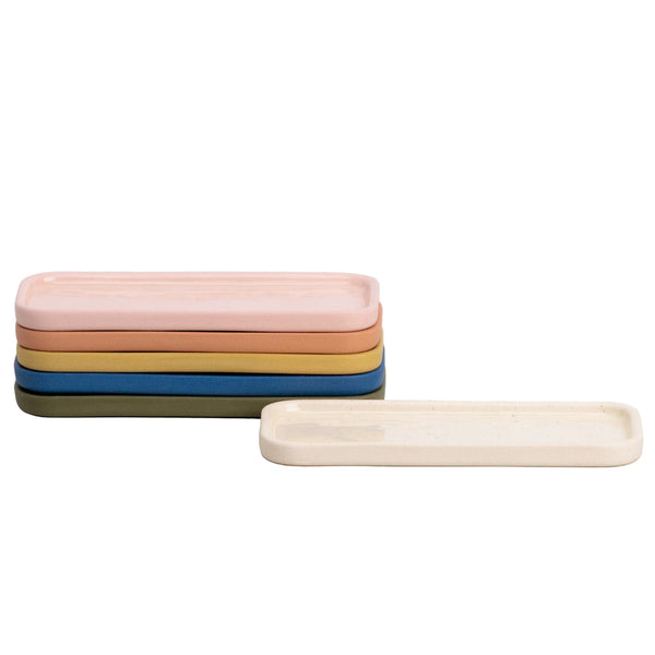 Stack of colorful ceramic trays on a light gray background