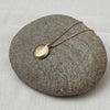 Gold necklace with a round pendant on a gray stone