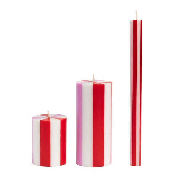Set of three striped candles in red and white on a light gray background