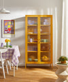 Yellow glass-fronted cabinet in a room with a table and chairs.